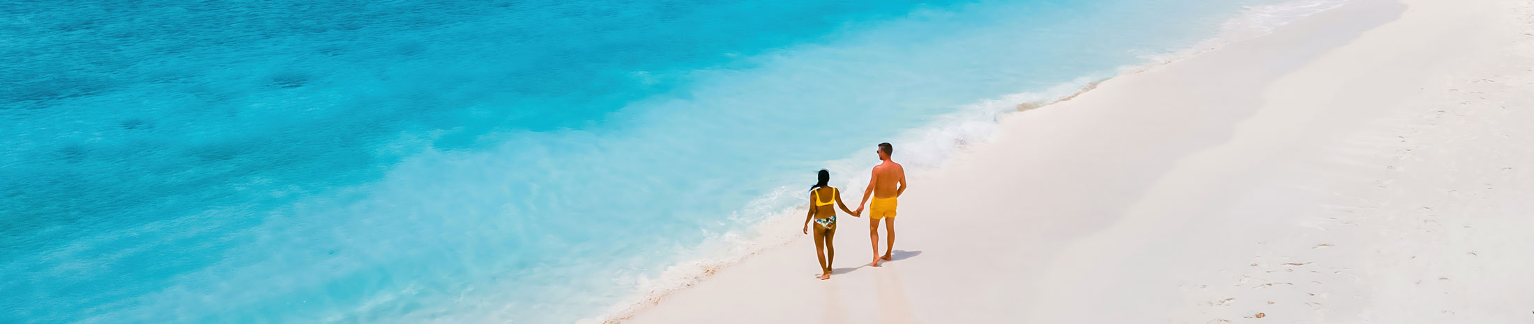 P&auml;rchen am Strand in Badebekleidung, blaues Wasser, Wellen, wei&szlig;er Strand